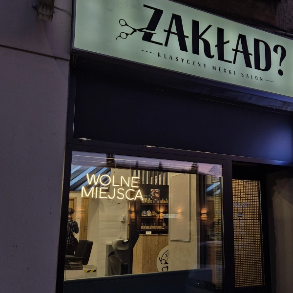 Neon sklepowy „WOLNE MIEJSCA” w witrynie salonu fryzjerskiego Zakład