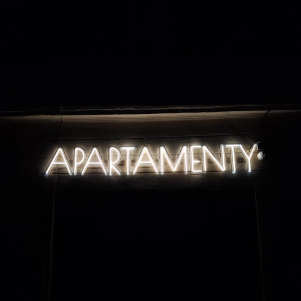 Neon zewnętrzny „APARTAMENTY” jako szyld reklamowy obiektu noclegowego